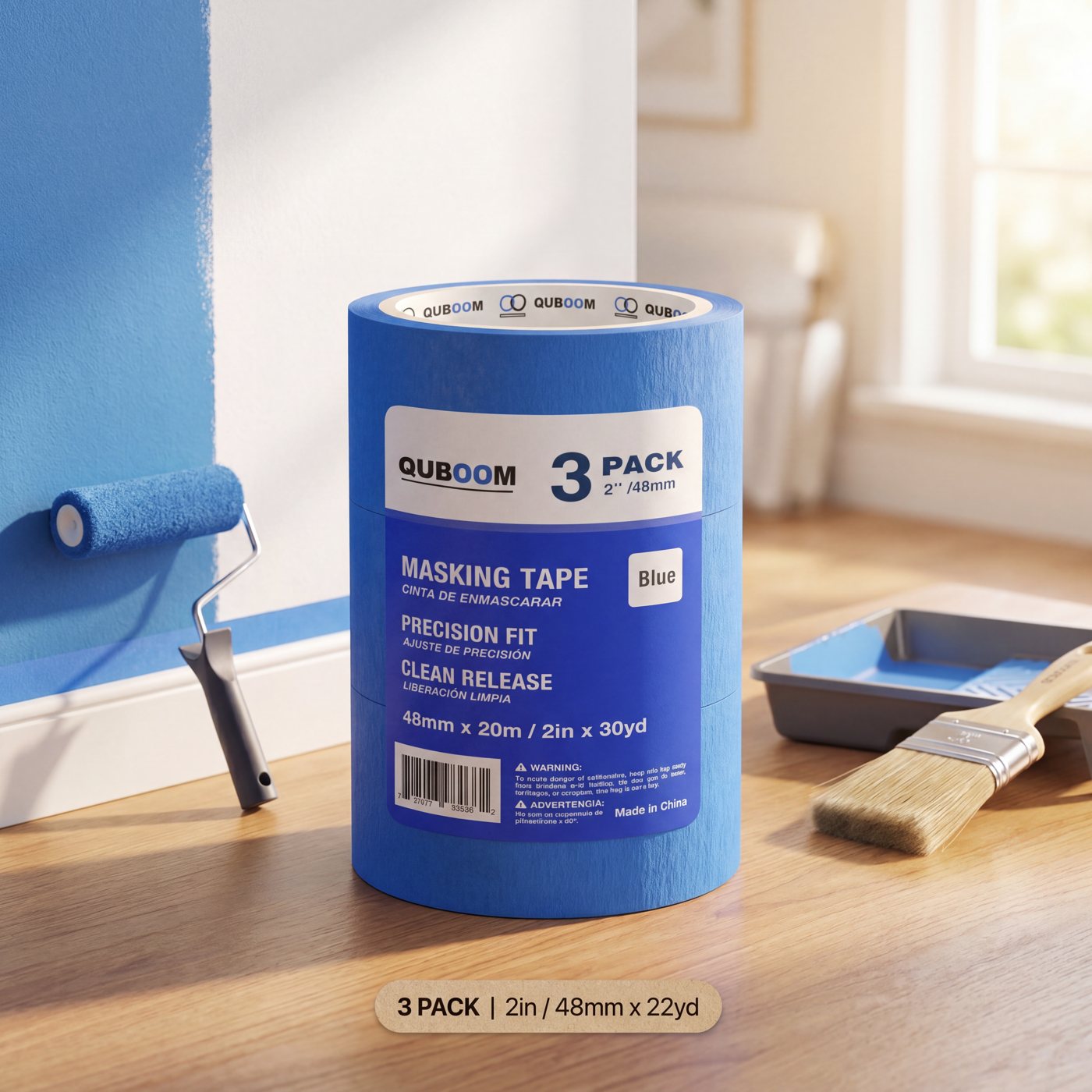 A Quboom 3-pack on a wooden floor beside a paint roller and a half-painted blue wall