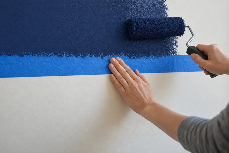 A roller painting navy over the top of the tape